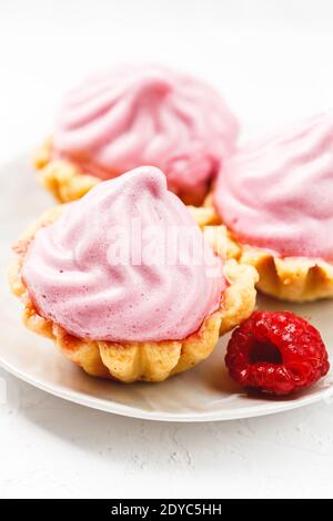 Mini cesti di torte con crema di lamponi serviti su piatto bianco Foto Stock