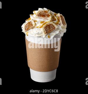 Bevanda al caffè ricoperta di panna montata, sciroppo di cioccolato e caramelle in tazza di carta per isolarsi su sfondo nero Foto Stock