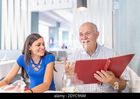L'uomo maturo e la giovane donna si divertono e sorridono, trascorrendo il tempo insieme Foto Stock