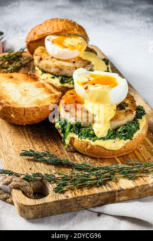 Delizioso hamburger di pesce con filetto di pesce, uova e spinaci su un brioche. Sfondo grigio. Vista dall'alto. Foto Stock