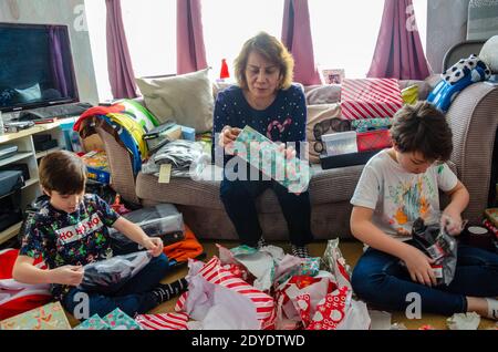 Una famiglia eccitatamente aperto regali di Natale insieme a casa il giorno di Natale. Foto Stock