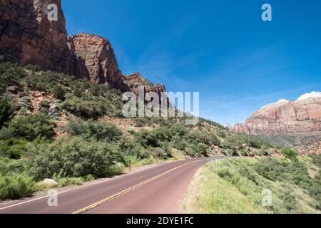 Un cielo blu chiaro su una strada lastricata curvilinea che va attraverso splendide scene della natura Foto Stock