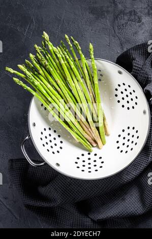 Asparagi verdi freschi del bambino in un colapasta. Sfondo nero. Vista dall'alto Foto Stock