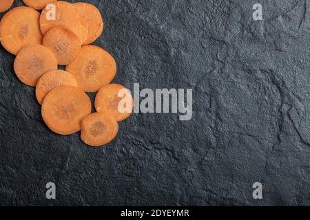 Carote fresche e biologiche a fette su sfondo nero Foto Stock