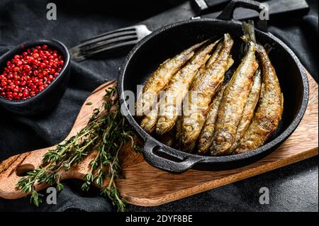 Il pesce di capelin fritto in pastella viene servito su una padella di metallo. Sfondo nero. Vista dall'alto Foto Stock