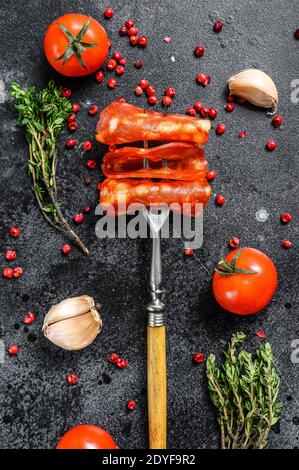 Salsiccia di chorizo a fette spagnole. Carne stagionata. Sfondo nero. Vista dall'alto Foto Stock