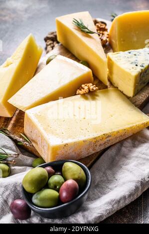 Collezione di formaggi svizzeri, olandesi, francesi, italiani con frutta a guscio e uva. Sfondo scuro. Vista dall'alto Foto Stock