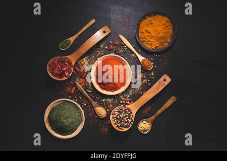 composizione con varietà di spezie ed erbe su sfondo nero vista dall'alto. Cucina ingredienti e condimenti concetto. Foto Stock