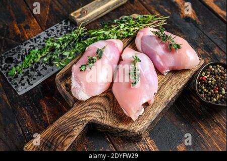 Filetto di coscia di pollo crudo senza pelle su un tagliere di legno. Sfondo nero. Vista dall'alto Foto Stock