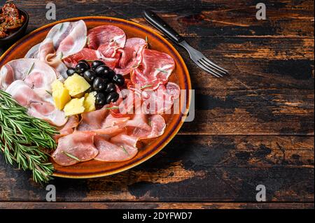 Piatto di carne italiana con prosciutto, bresaola, pancetta, salame e parmigiano. Sfondo di legno scuro. Vista dall'alto. Spazio di copia Foto Stock