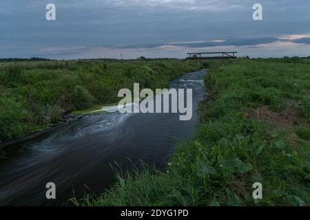 Piccolo fiume e erba verde, esposizione lunga, sera d'estate Foto Stock