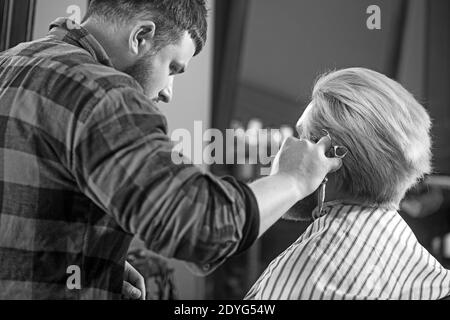 Vista posteriore di barbiere uomo sta facendo taglio di capelli. Foto Stock