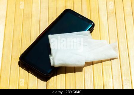 Smartphone moderno e un panno umido, tessuto umido sul tavolo cellulare disinfezione, pulizia, igienizzazione, tecnologia e igiene durante covid 19 Foto Stock