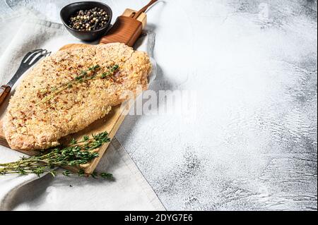 Schnitzel di pollo crudo in pangrattato. Sfondo grigio. Vista dall'alto. Spazio di copia Foto Stock