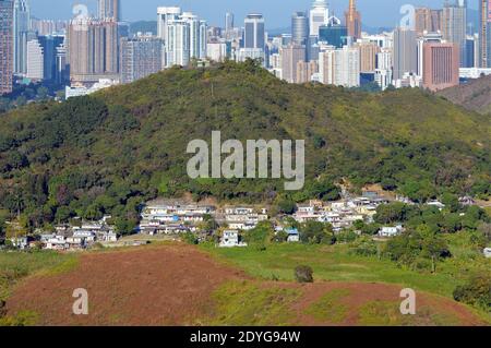 Shun Yee San Tsuen, un villaggio nel nord di Hong Kong, con lo skyline di Shenzhen, Cina sullo sfondo Foto Stock