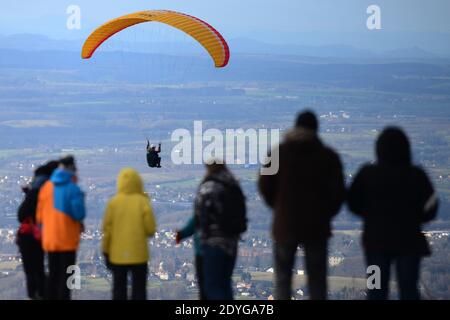 Kozakov, Repubblica Ceca. 26 Dicembre 2020. I turisti si levano in piedi sulla terrazza panoramica e guardano un parapendio durante il volo annuale di Natale sopra il Kozakov nel paradiso Boemo nella Repubblica Ceca. Il parapendio è uno sport di volo ricreativo e competitivo. Il pilota si trova in un'imbracatura sospesa sotto un'ala in tessuto, la cui forma è formata dalla pressione dell'aria che entra nelle bocchette nella parte anteriore dell'ala. *** Local Caption Credit: Slavek Ruta/ZUMA Wire/Alamy Live News Foto Stock