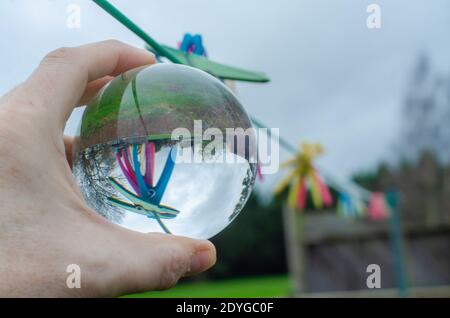 Pioli su una linea di lavaggio in un giardino visto capovolto in una sfera di cristallo di vetro che agisce come una lente e provoca la rifrazione. Foto Stock
