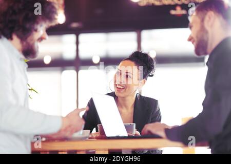 Donna d'affari felice in un caffè con colleghe. Riunione creativa fuori sede. Foto Stock