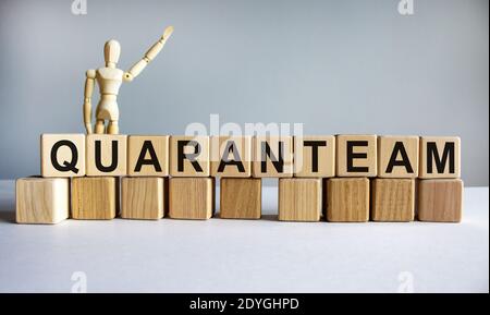 Nuova parola simbolo Quaranteam. Cubetti di legno con la parola 'quaranteam'. Modello di legno di umano. Splendido sfondo bianco, spazio per la copia. Covid-19 pandemia Foto Stock
