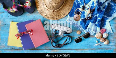 vacanze estive e vacanze estive, posate con libri, macchina fotografica, infradito, conchiglie, occhiali da sole, telo da spiaggia, cappello di paglia Foto Stock