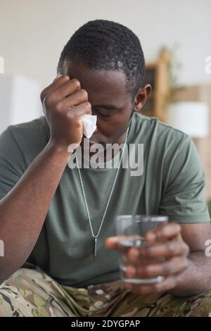 Giovane africano seduto in depressione con un bicchiere d'acqua Foto Stock