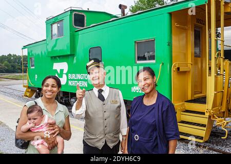 Alabama Calera Heart of Dixie Railroad Museum, uomo anziano maschile direttore uniforme spiegare, madre nera nonna bambino donne verde caboose pointin Foto Stock