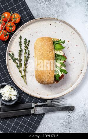 Panino di ciabatta con formaggio di capra fresco, marmellata di pere e rucola. Sfondo grigio. Vista dall'alto Foto Stock