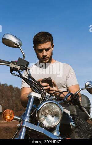 Motociclista che guarda il cellulare durante un percorso Foto Stock