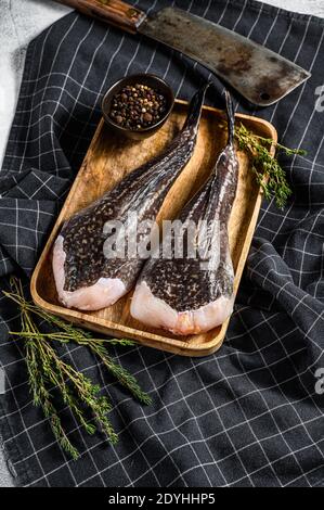 Rana pescatrice cruda su un vassoio di legno con una scissione. Sfondo grigio. Vista dall'alto Foto Stock