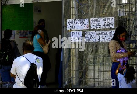 Guacara, Carabobo, Venezuela. 26 Dicembre 2020. 26 dicembre 2020, Hernandez, Guacara, Carabobo, la gente aspetta per fare gli acquisti di cibo alle porte di un negozio che pubblica i prezzi in dollari. La valuta americana è già un riferimento di costo in Venezuela a causa dell'iperinflazione e della costante fluttuazione del valore del dollaro. A Guacara, Stato di Carabobo. Foto: Juan Carlos Hernandez. Credit: Juan Carlos Hernandez/ZUMA Wire/Alamy Live News Foto Stock