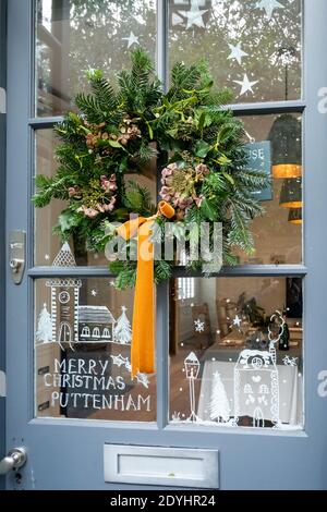 Corona di Natale fatta con pino, edera e mistletoe su una porta a Puttenham, Surrey, Regno Unito. Decorazioni naturali di stagione. Foto Stock