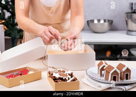 Donna che avvolge i biscotti di pan di zenzero di natale nelle scatole di festa. Foto Stock