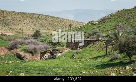 rovine di un mulino di pietra di epoca ottomana su wadi letto del torrente milkha nella valle del giordano con le montagne di giordania sullo sfondo Foto Stock