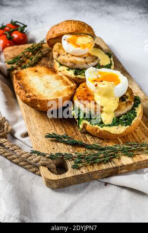 Hamburger di pesce fatto in casa con filetto di merluzzo, uova e spinaci su un brioche. Sfondo grigio. Vista dall'alto Foto Stock