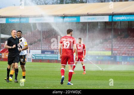 Crawley, Regno Unito. 26 Dicembre 2020. L'arbitro David Rock e i giocatori di Crawley Town e Newport County vedono il lato divertente come gli sprinkler si accendono durante la seconda metà. EFL Skybet Football League Two match, Crawley Town contro Newport County al People's Pension Stadium di Crawley, West Sussex, Inghilterra, sabato 26 dicembre 2020. Questa immagine può essere utilizzata solo per scopi editoriali. Solo per uso editoriale, è richiesta una licenza per uso commerciale. Nessun uso in scommesse, giochi o un singolo club/campionato/giocatore publications.pic by Credit: Andrew Orchard sports photography/Alamy Live News Foto Stock