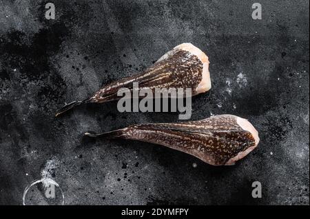 Rana pescatrice grezza senza testa. Sfondo nero. Vista dall'alto Foto Stock