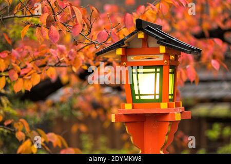 Kyoto Giappone le foglie di caduta rosse, arancioni e gialle si aggrappano sulla tradizionale lanterna dipinta di arancio vicino al santuario di Tatsumi Daimyojin sulla via Shinbashi Dori Foto Stock