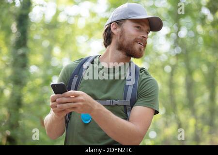 uomo con zaino che utilizza smartphone su una natura bellissima Foto Stock