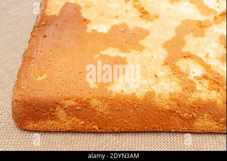 Torta di spugna fatta in casa, in portoghese Pao De lo. Parte inferiore dell'impasto per torte cotto. Isolato su sfondo juto. Primo piano. Shot orizzontale. Foto Stock