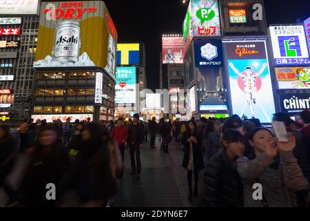 Pannelli illuminati di notte sull'affollato Ponte Ebissubashi sul canale Dotonbori. Foto Stock