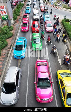 Auto colorate, taxi e motociclette che fermano a un incrocio durante l'ora di punta nel centro di Bangkok, Asia Foto Stock