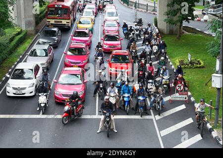 Auto colorate, taxi e motociclette che fermano a un incrocio durante l'ora di punta nel centro di Bangkok, Asia Foto Stock