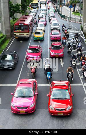 Auto colorate, taxi e motociclette che fermano a un incrocio durante l'ora di punta nel centro di Bangkok, Asia Foto Stock