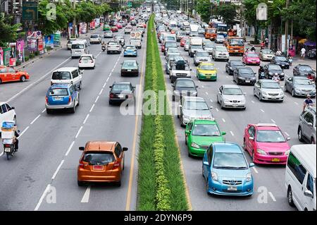 Auto colorate, taxi e motociclette su una grande autostrada Rama durante l'ora di punta nel centro di Bangkok, città verde, Asia Foto Stock