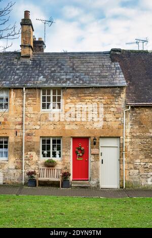 Corona di Natale su una porta di cottage dipinto di rosso a Chipping campden. Cotswolds, Gloucestershire, Inghilterra Foto Stock