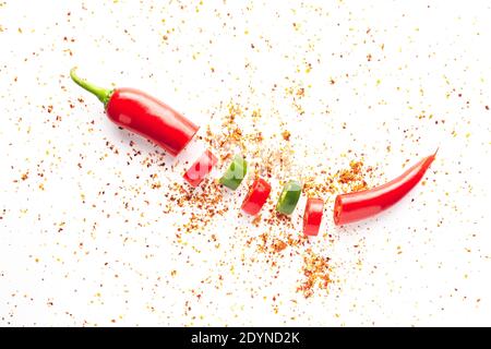 Peperoncino rosso e verde affettato e polvere di peperoncino sparsa su sfondo bianco. Gastronomia e condimenti di cucina. Foto Stock