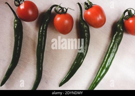 Peperoni verdi e pomodori ciliegini. Elementi ripetitivi nella fotografia alimentare. Elaborazione artistica, messa a fuoco selettiva. Foto Stock