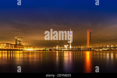 Vista notturna di Dusseldorf sulla riva del Reno in Germania; Rheinturm e grattacieli Foto Stock