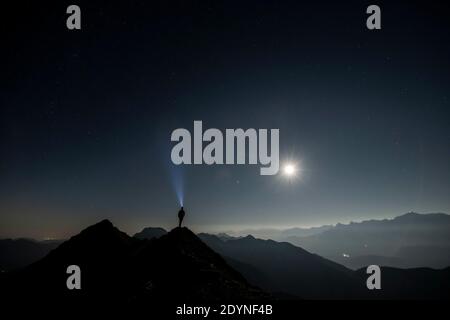 Alpinista in cima cresta con luna piena e cielo stellato, sullo sfondo Alpi Ammergau, Reutte, Alpi Ammergau, Tirolo, Austria Foto Stock