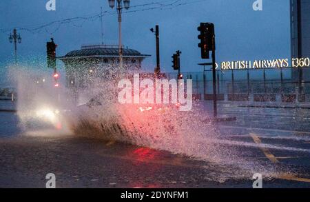 Brighton UK 27 dicembre 2020 - UN'automobile guida attraverso l'inondazione sul lungomare di Brighton presto nella mattina mentre Storm Bella batte oggi la Gran Bretagna con i venti forti e la pioggia pesante che causano l'inondazione e danni in alcune zone: Credit Simon Dack / Alamy Live News Foto Stock